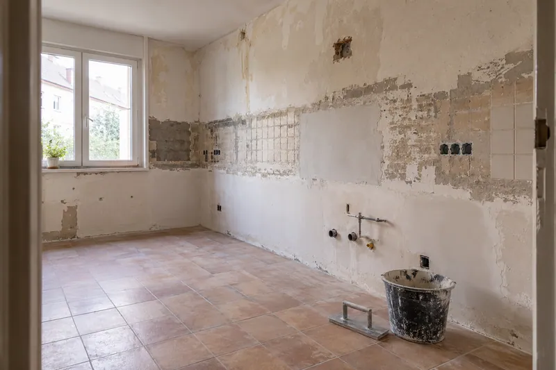 Visualización conceptual IA: Cocina sin muebles con paredes en preparación y zonas de enlucido.